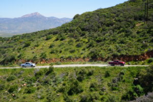 The new field truck (silver) joining older truck (red) on field trips, driving down dirt path along the mountain side.